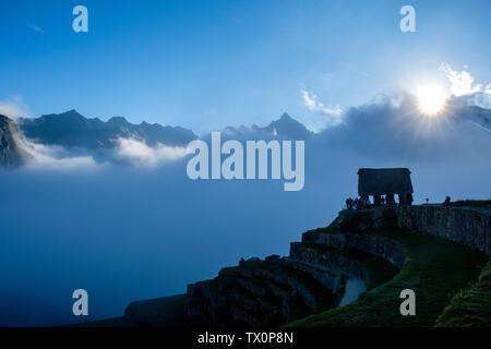 Early morning foggy view of Machu Picchu guardhouse, Sacred Valley of the Incas. Tourists waiting for the first light at sunrise, Machu Picchu Peru. Stock Photo