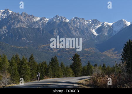 A lone cyclist on a mountain road on a sunny autumn afternoon Stock Photo