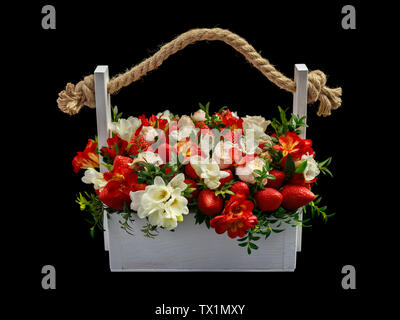 White wooden box filled with white and red roses and ripe strawberries isolated on white background Stock Photo