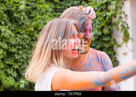 Festival holi, people concept - young couple taking selfie in colourful dirty clothes Stock Photo