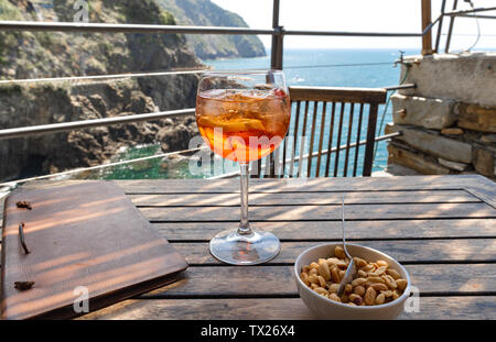 Aperol spritz cocktail close up on a wooden table in a restaurant. Riomaggiore in Cinque Terre, Italy Stock Photo