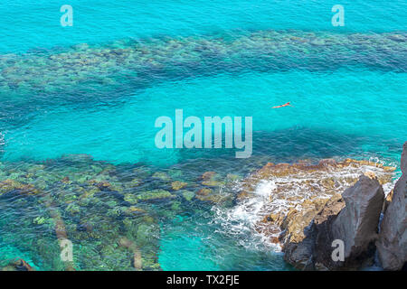 Aerial view of man snorkeling in clear tropical sea water – male swimming in beautiful bay with coral background on sunny day – adventure in ocean Stock Photo
