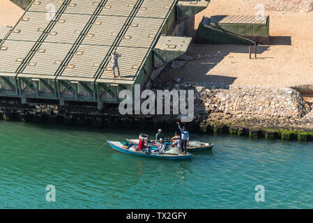 Ismailia, Egypt - November 5, 2017: Fishermen in wooden boat catch fish net on the New Suez Canal. Pontoons bridge on the shore of canal near Ismailia Stock Photo