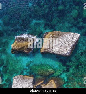 Two large boulders protrude from the water at the rocky shore. top view. Stock Photo