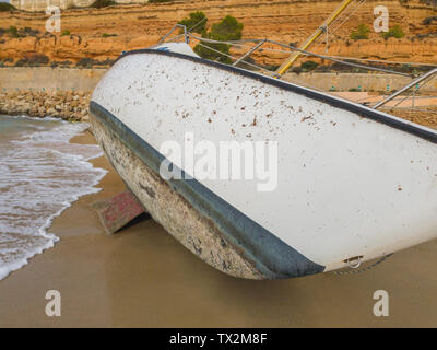 The hull of a sailboat thrown by a storm on the shore of the sea. Stock Photo