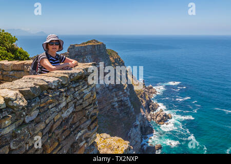 Woman watching view at Cape of good hope, looking towards the camera, Cape Point, Cape Town, South Africa Stock Photo