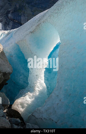 A big hole in a glacier with melting ice and falling water drops, Briksdal Glacier, Norway Stock Photo