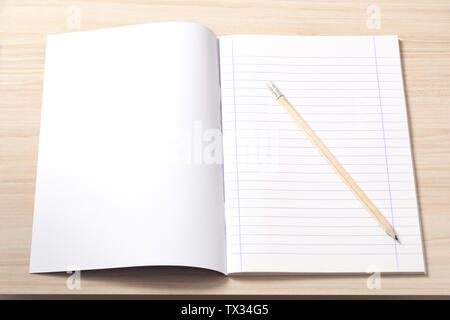 Open notebook with blank sheets and a pencil on a desk, workplace. Stock Photo