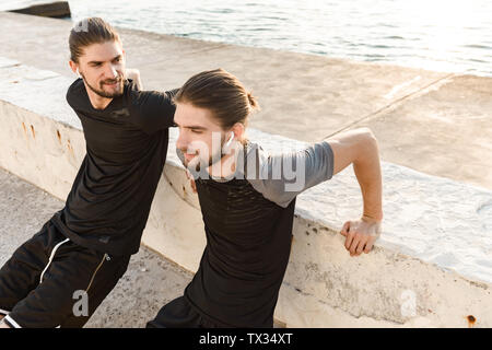 Two attractive twin brothers doing exercises outdoors Stock Photo