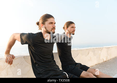 Two attractive twin brothers doing exercises outdoors Stock Photo