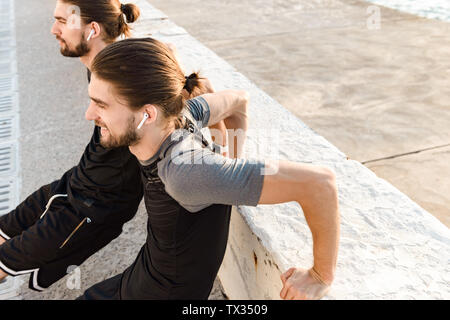 Two attractive twin brothers doing exercises outdoors Stock Photo