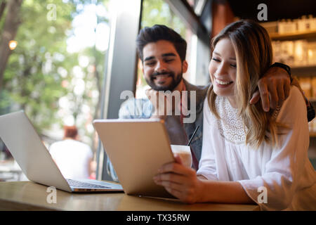 Young couple is working in cafe on laptop and smiling. Stock Photo