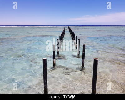 metal piles for pier in the sea. Clearly visible clear sea water and the blue sky on the horizon. space for text Stock Photo