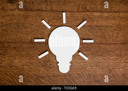 View from above paper light bulb on wooden surface Stock Photo