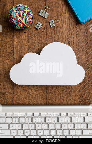 View from above paper cloud on wooden desk above computer keyboard Stock Photo