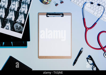 View from above blank paper on clipboard next to x-rays and stethoscope Stock Photo