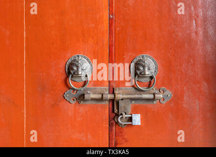 A red wooden door with a lion's head buckle. Stock Photo