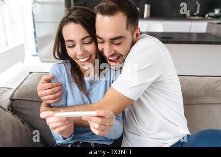 Lovely young couple holdingpregnancy test, celebrating Stock Photo