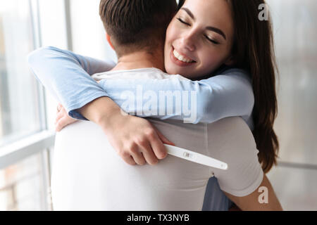 Lovely young couple holdingpregnancy test, celebrating Stock Photo