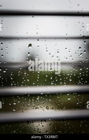 Raindrops on a window pane seen through blinds. Stock Photo
