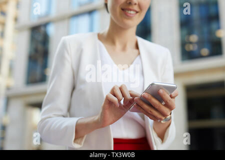 Mid-section portrait of smiling businesswoman using smartphone outdoors, copy space Stock Photo