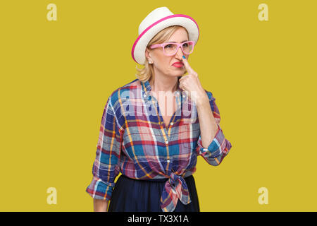 You are liar. Portrait of angry modern stylish mature woman in casual style with hat, eyeglasses standing looking and touching nose with lie gesture. Stock Photo