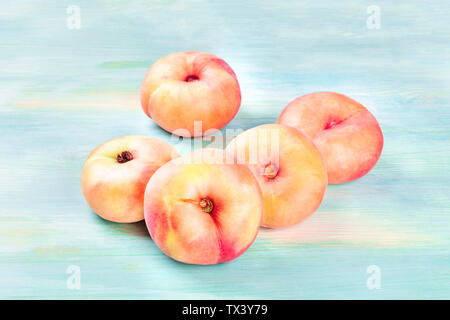 Vibrant organic flat saturn peaches on a teal background Stock Photo