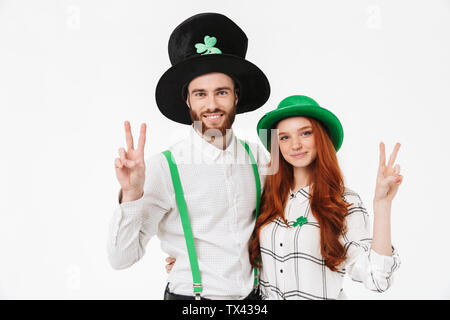 Happy young couple wearing costumes, celebrating St.Patrick 's Day isolated over white background, having fun together, peace gesture Stock Photo