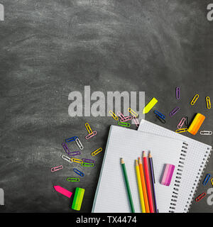 Educational supplies notebooks pens pencils against the background of a chalk board. Concept back to school. Flat layout top view. Copy space. Square Stock Photo