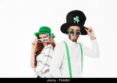 Happy young couple wearing costumes, celebrating St.Patrick 's Day isolated over white background, having fun together, posing with sunglasses Stock Photo
