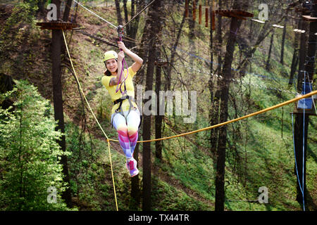 Young woman wearing yellow t-shirt and helmet in a rope course Stock Photo