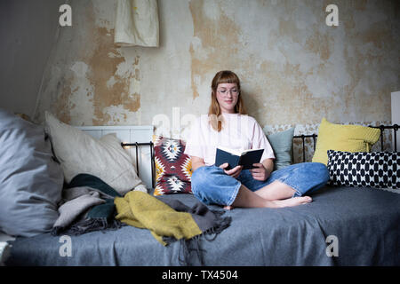 Female student reading a book in her room Stock Photo