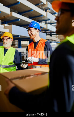 Happy workers talking in factory warehouse Stock Photo