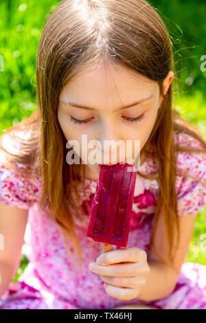 Portrait of girl eating popsicle in garden Stock Photo