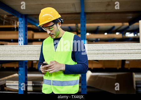 Worker using cell phone in factory warehouse Stock Photo