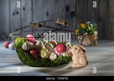 Easter eggs in wire basket with Easter bunny in the foreground Stock Photo