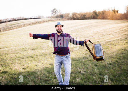 Bearded man with accordion dancing on a meadow Stock Photo