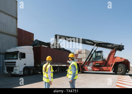 Workers in front of cargo containers on industrial site Stock Photo