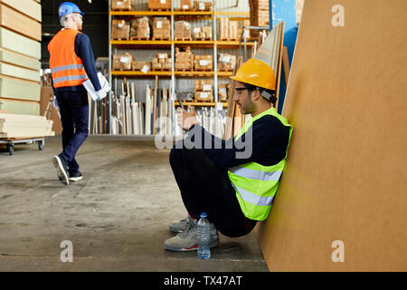 Worker using cell phone during a break in factory Stock Photo