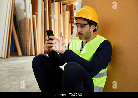 Worker using cell phone during a break in factory Stock Photo