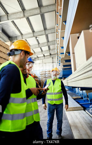 Workers talking in factory warehouse Stock Photo