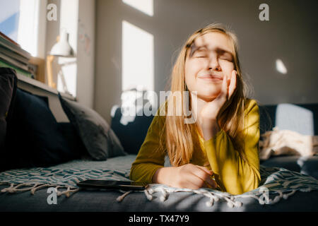 Girl lying on couch at home in sunshine Stock Photo