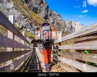 Spain, Asturia, Cantabrian Mountains, senior man on a hiking trip crossing a bridge