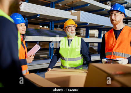 Workers talking in factory warehouse Stock Photo