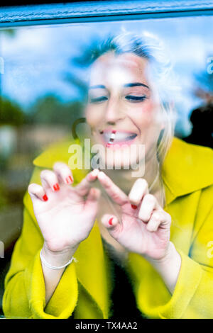 Woman drawing a heart on a windowpane Stock Photo