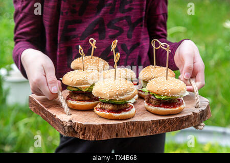 Girl holding wooden tray with mini burger Stock Photo