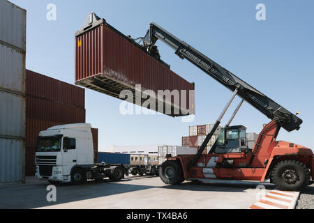 Crane lifting cargo container on truck on industrial site Stock Photo