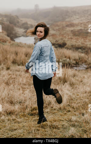 UK, Scotland, Isle of Skye, young woman running in rural landscape Stock Photo