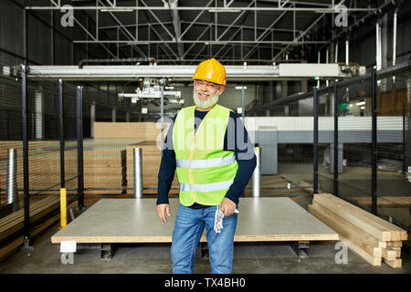 Portrait of smiling mature worker in factory warehouse Stock Photo