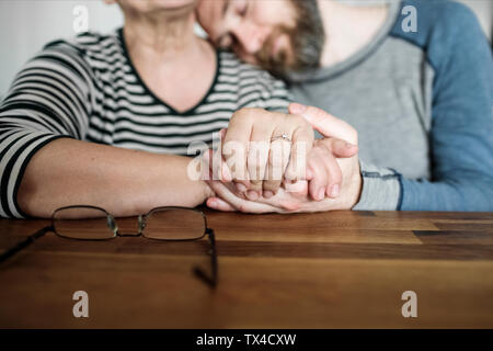 Close-up of affectionate adult son and senior mother holding hands at home Stock Photo